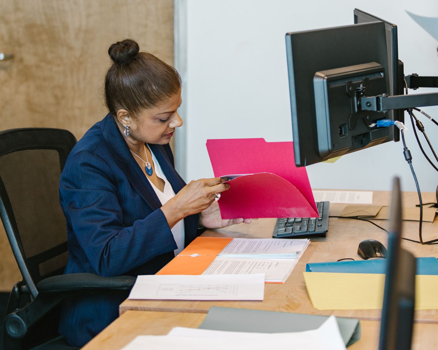Escrow professional reviewing a folder of documents at her desk